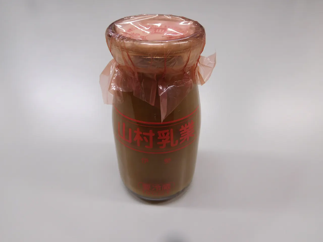 A glass bottle of coffee milk with a paper cap tied with a ribbon