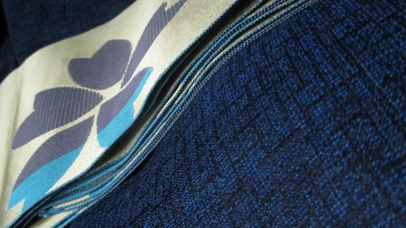 Close-up of a folded indigo cotton yukata with a cream obi printed with a leaf pattern