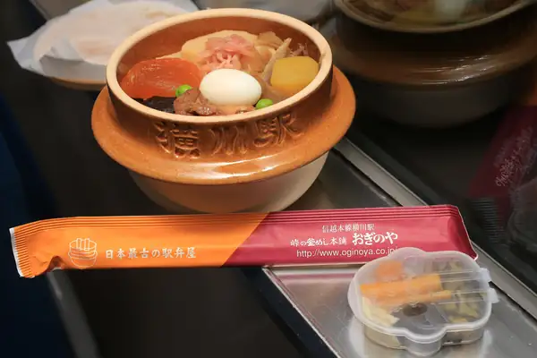 An opened Tōge no Kamameshi: rice topped with chicken, a quail egg, chestnut and vegetables in a brown clay pot